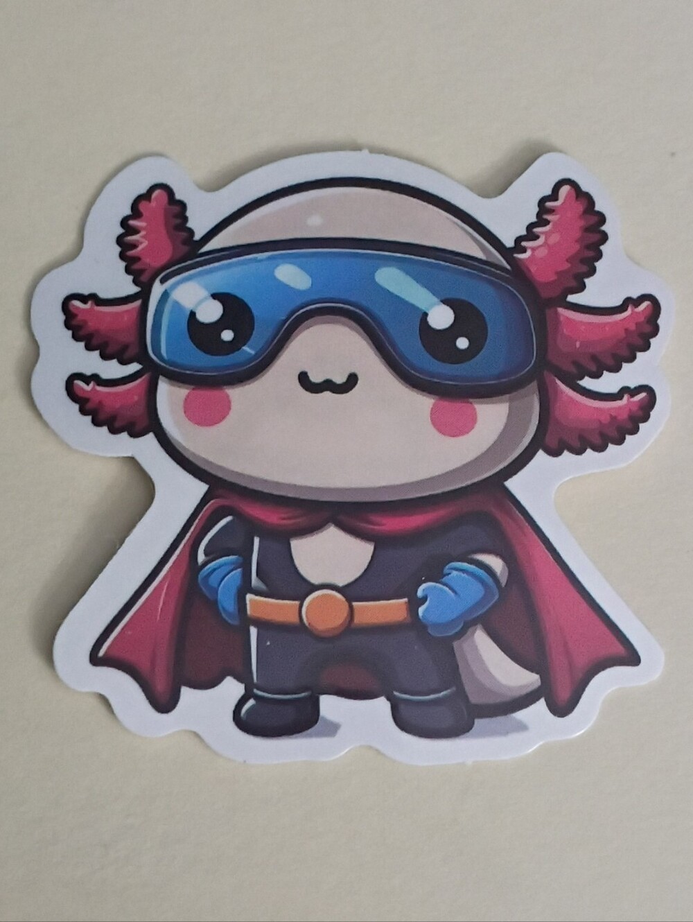 10/$10 Sticker - Axolotl Pink Cream Color Dressed As Superhero w/ Cape & Goggles